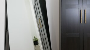A room with a dark wooden wardrobe, a large mirror, and a small potted plant. - Barocci Home (Rome)