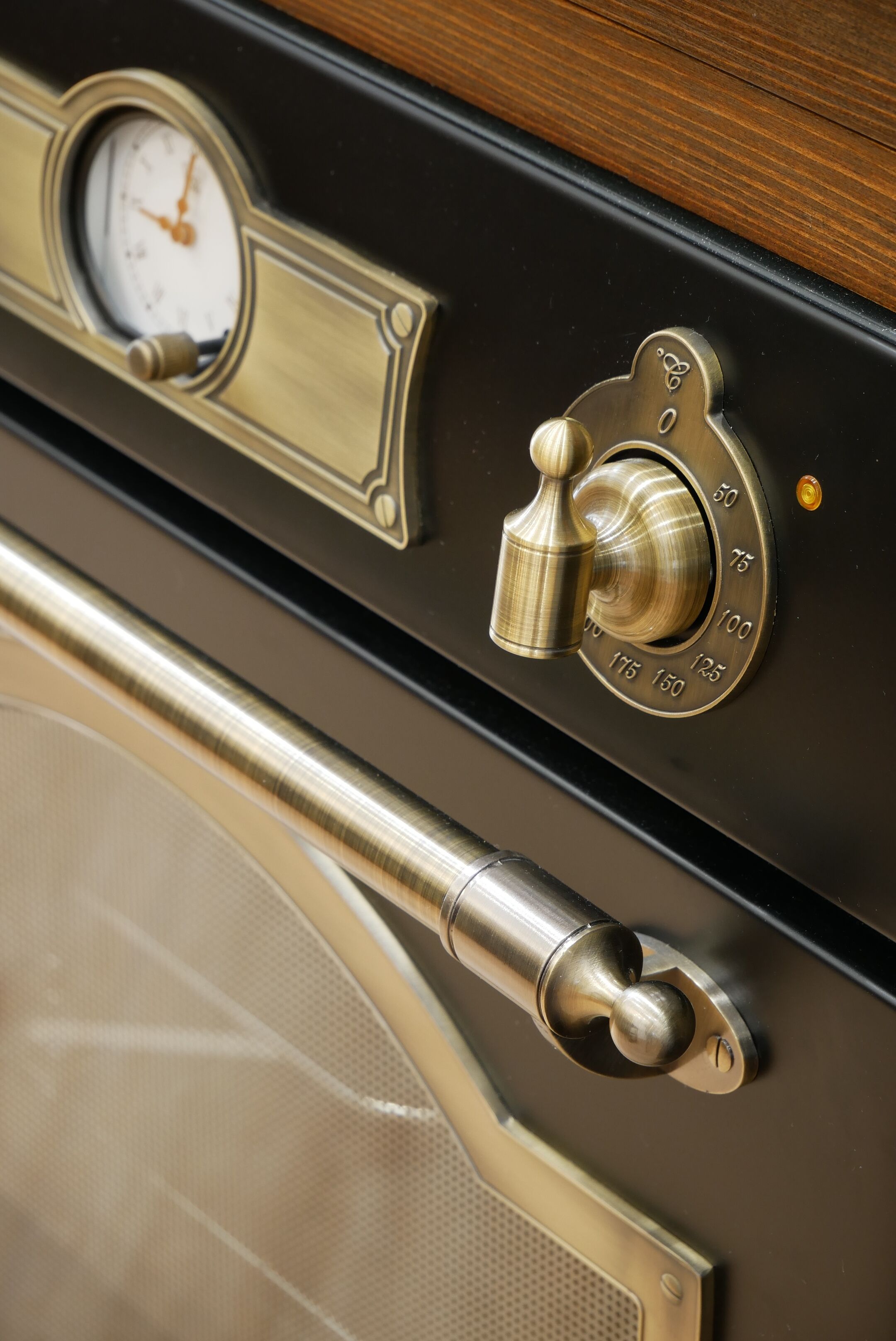 A close-up of a vintage-style oven door with a pressure gauge and a temperature dial.