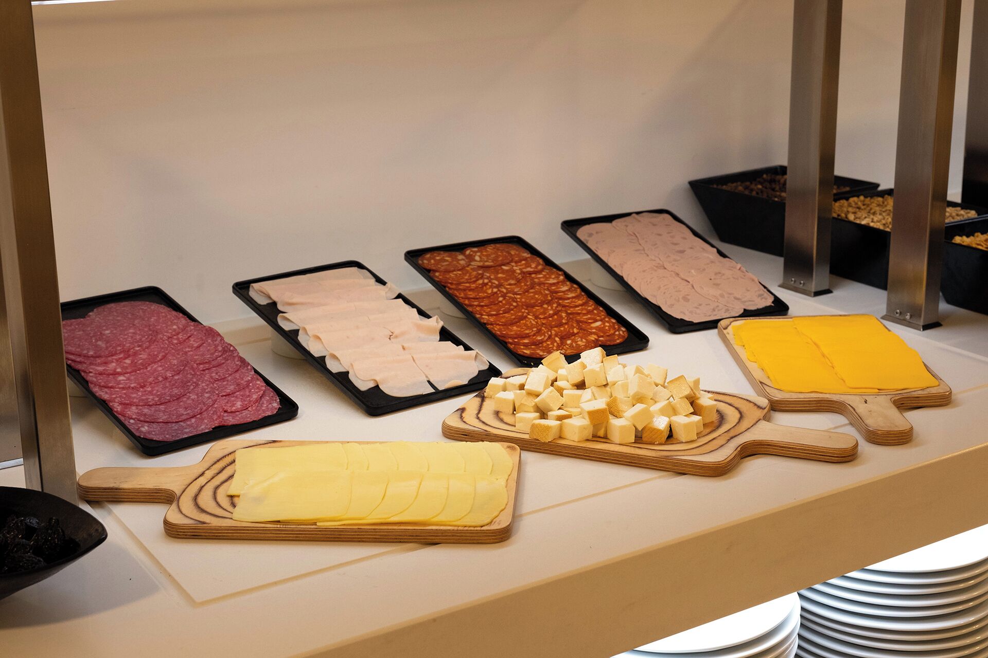 Buffet com diversos alimentos, incluindo carnes fatiadas, queijos e outros pratos preparados.