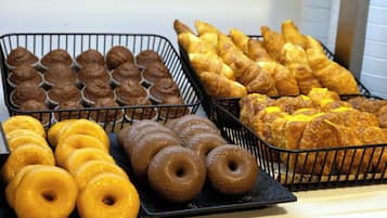 Tabletts mit Backwaren, darunter Muffins, Croissants und Donuts.