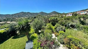 Una zona residencial en una ladera con casas, vegetación exuberante y un cielo azul despejado.