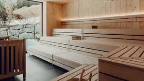 A modern spa room with wooden paneling, a stone wall, and a large window. - Hotel Murrer 3S Double Room 104 with Mountain View, Spa and Wellness Area (Sarntal)