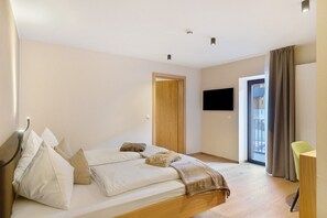 Une chambre à coucher avec un lit, une télévision, une porte et une fenêtre.