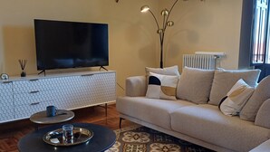 A living room with a sofa, a TV on a stand, a lamp, a radiator, and a patterned rug. - Luxury Sea Palazzo with sea view terrace (Trani)