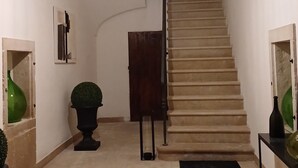 A staircase with a light fixture above, a potted plant, and a door at the bottom. - Luxury Sea Palazzo with sea view terrace (Trani)