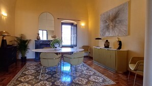 A dining area with a round table, chairs, a vase, and a potted plant. - Luxury Sea Palazzo with sea view terrace (Trani)