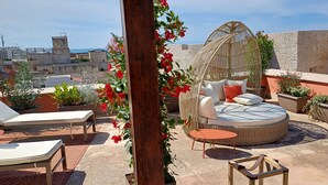 A rooftop terrace with lounge chairs, a round seating area with cushions, and potted plants. - Luxury Sea Palazzo with sea view terrace (Trani)