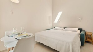 Ein modernes Hotelzimmer mit einem Bett, einem kleinen Tisch mit Stuhl und einem Nachttisch.
