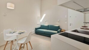 Eine moderne Küche mit eingebautem Herd, weißen Schränken und einem Essbereich mit weißem Tisch und Stühlen.