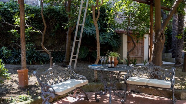 En terrasse med jerngittermøbler, en stige og krukkeplanter.