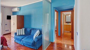 Una habitación con pared azul, un armario de madera, un sofá con cojines a rayas y un separador de vidrio.