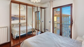 Un dormitorio con una cama grande, un armario con vistas, una lámpara de techo y un balcón también con vistas.