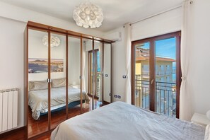 Ein Schlafzimmer mit einem großen Bett, einem Kleiderschrank mit Blick, einer Deckenleuchte und einem Balkon mit Aussicht.