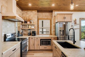 Una cucina moderna con zoccolo in pietra, mobili in legno, elettrodomestici in acciaio inossidabile e una finestra vista.
