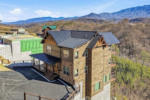 Un edificio a più piani con facciata in legno e tetto spiovente, immerso in un paesaggio montuoso.