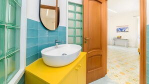 A bathroom with a round sink, a mirror, and a wooden door. - 'Positano Luxury' Room with Balcony, Wi-Fi and Air Conditioning (Meta)