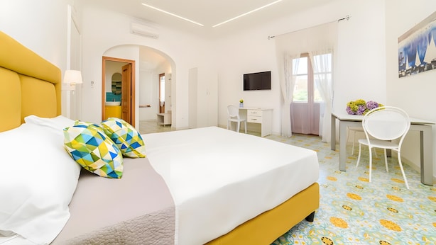A hotel room with a bed, a desk, a chair, and a TV. - 'Positano Luxury' Room with Balcony, Wi-Fi and Air Conditioning (Meta)
