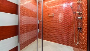 A modern bathroom with a glass shower enclosure, a tiled floor, and a wall with a honeycomb pattern. - Room 'Sorrento Luxury' with Wi-Fi and Air Conditioning (Meta)
