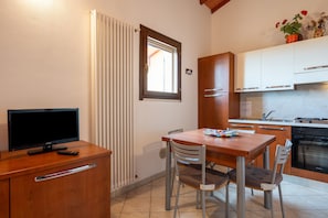 Une cuisine de taille réduite comprenant une table à manger, des chaises, un téléviseur et un réfrigérateur.