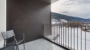 Un balcon avec une chaise en métal, une vue sur un paysage enneigé et une montagne en arrière-plan.