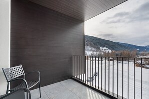 A balcony with a metal chair, a view of a snowy landscape, and a mountain in the background. - Hotel Murrer Double Room 306 with Mountain View, Spa and Wellness Area (Sarntal)