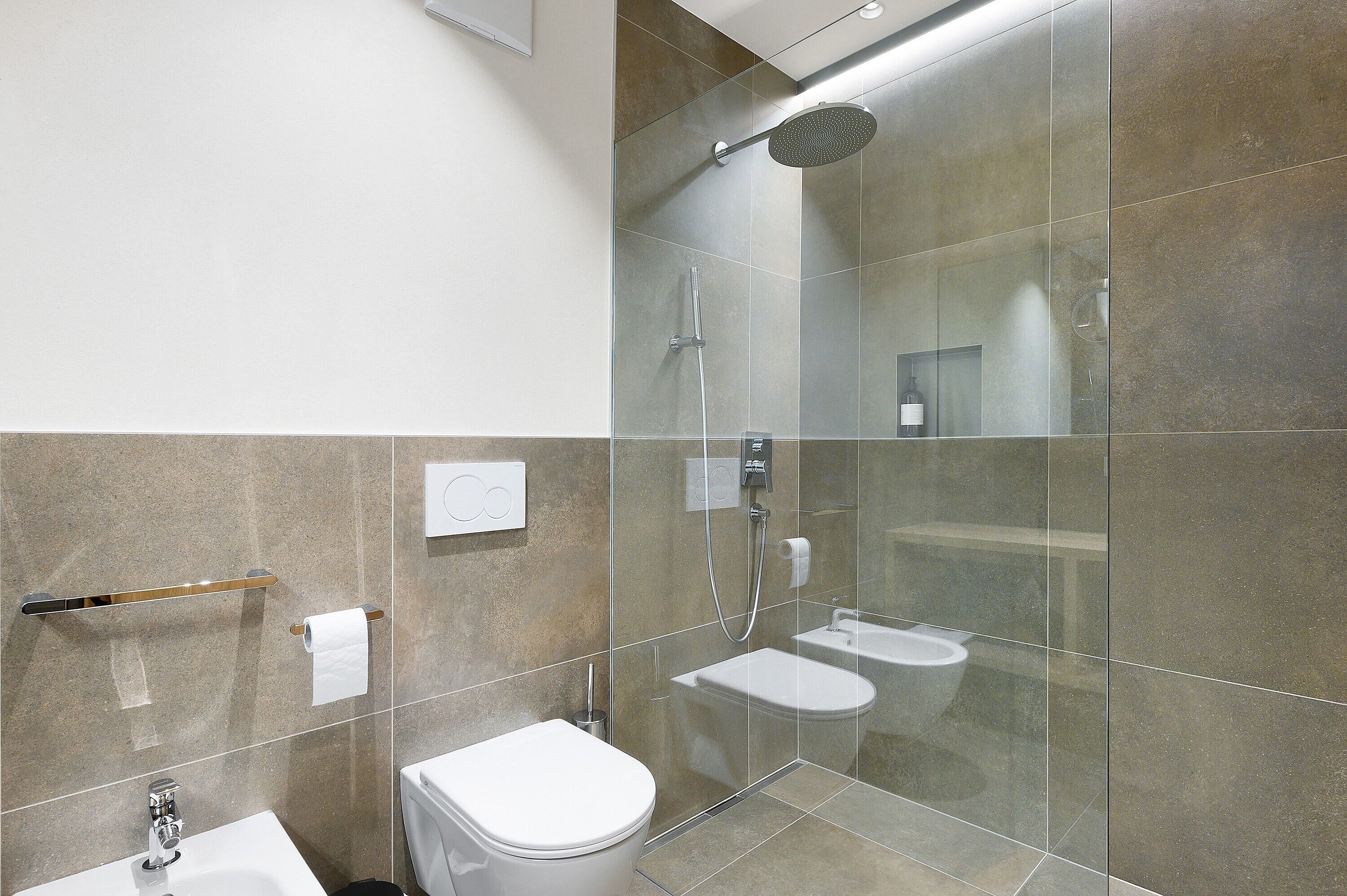 A modern bathroom with a glass-enclosed shower, a toilet, and a sink.