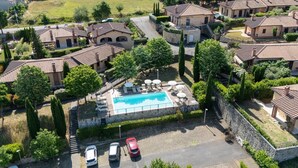 Un quartier résidentiel avec des maisons, une piscine et des voitures garées.