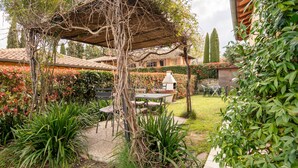 Un jardin agrémenté d’une pergola, d’un espace salon extérieur et d’un coin barbecue.