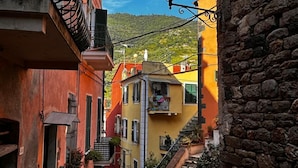Eine enge Straße mit bunten Häusern, einer Steinmauer und einer Treppe, die zu einer höheren Ebene führt.