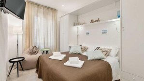 Ein Hotelzimmer mit Bett, Sofa, kleinem Tisch und Fernseher.