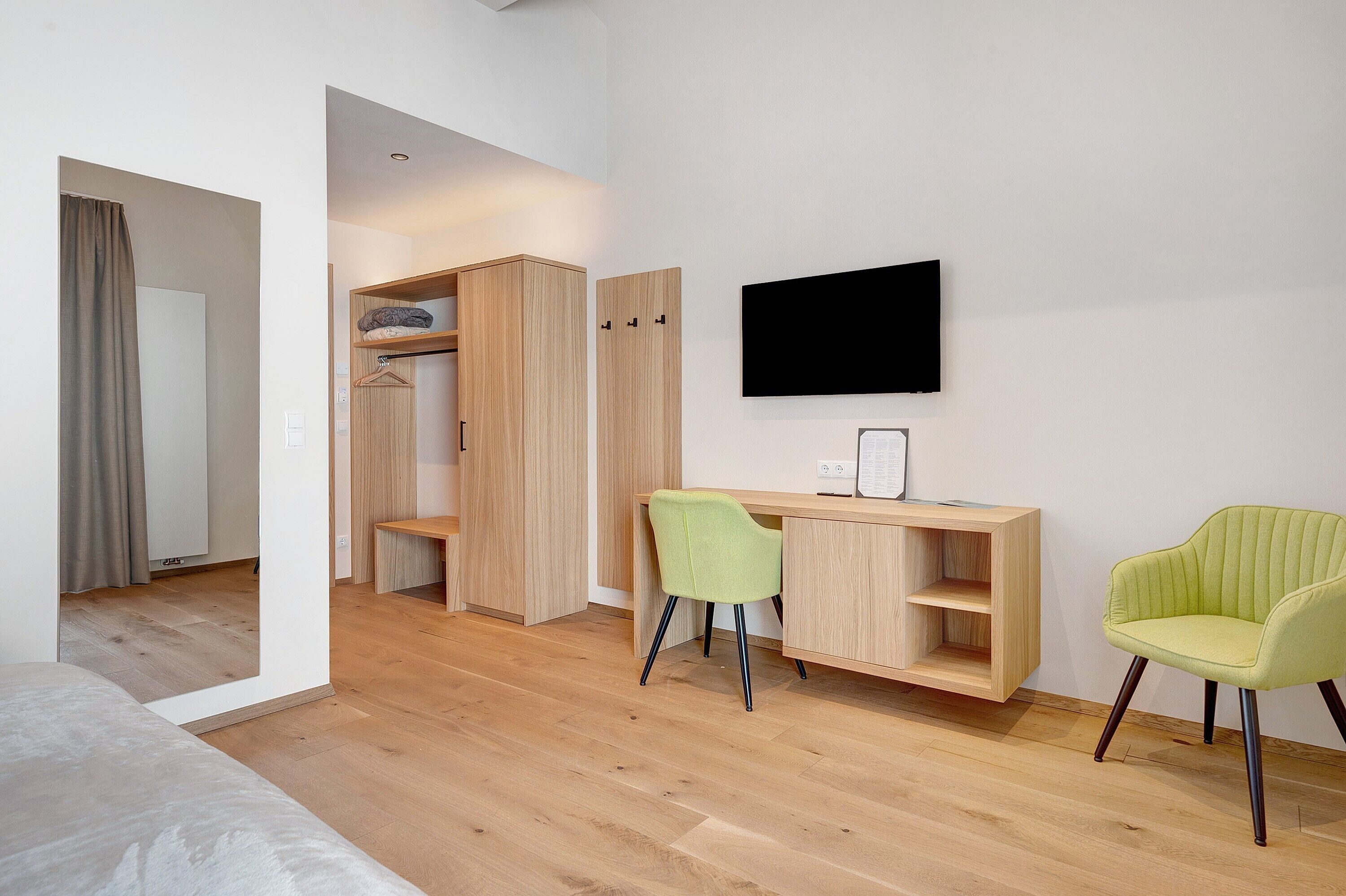 A modern room with a wooden desk, two chairs, a TV, and a wardrobe.