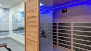 Una habitación con un separador de madera, un reloj digital y vista al mar a través de un ventanal grande.