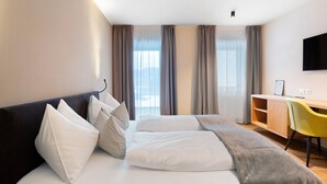 A hotel room with a bed, a desk, a chair, and a TV. - Hotel Murrer 3S Double Room 207 with Mountain View, Spa and Wellness Area (Sarntal)