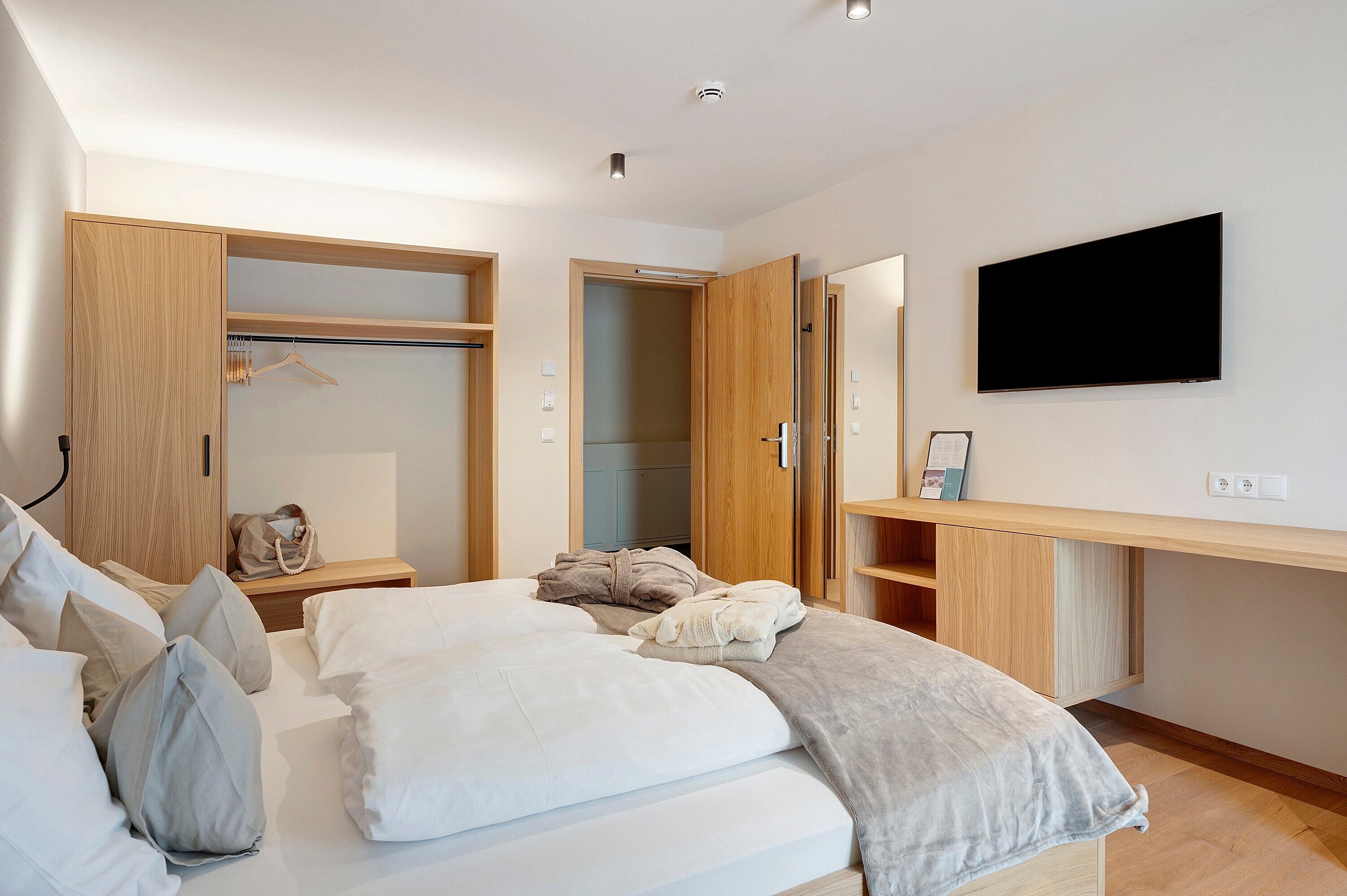Une chambre à coucher moderne avec un lit, une armoire, un bureau et un téléviseur.