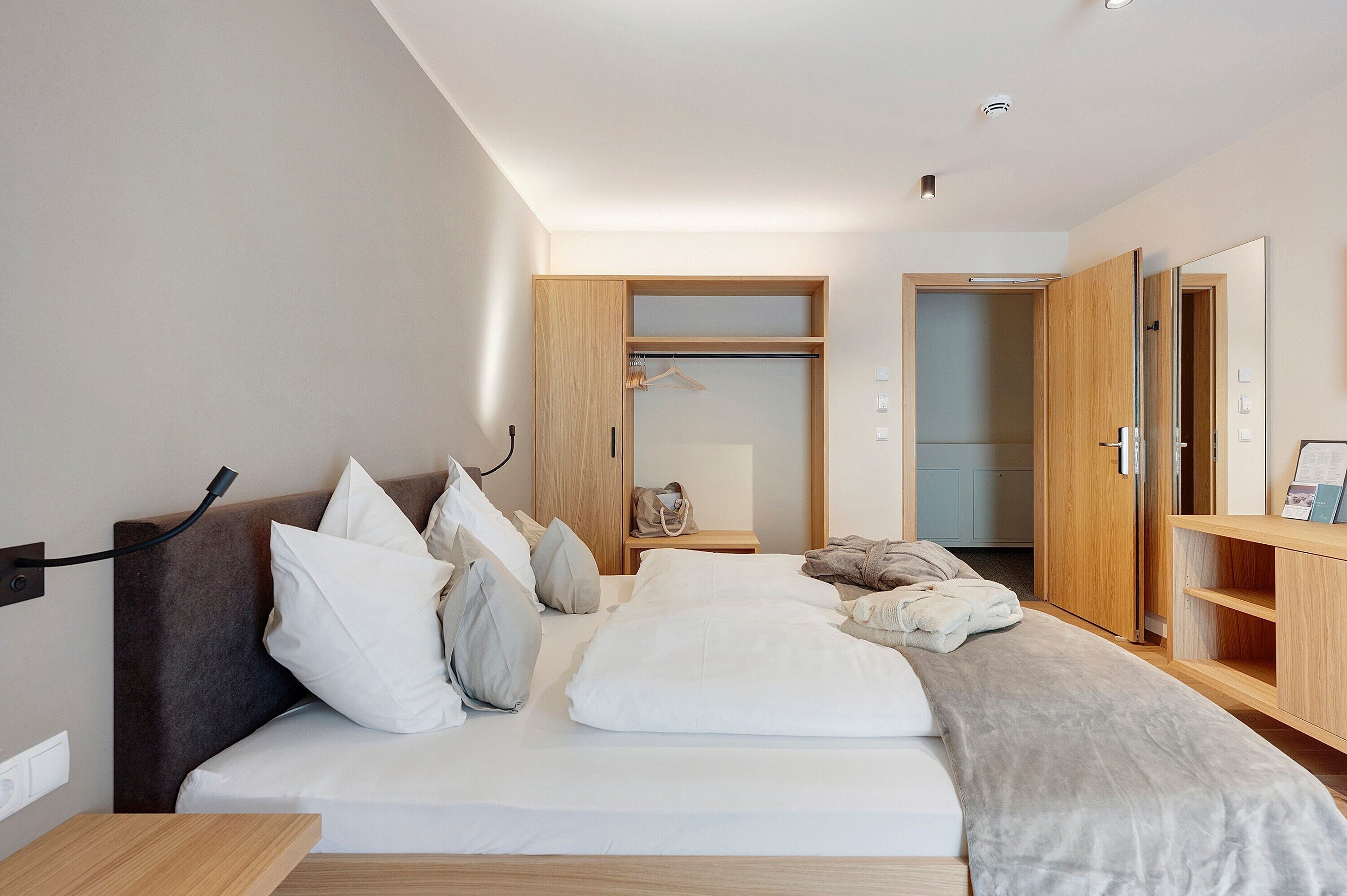 Een moderne slaapkamer met een bed, nachtkastje, garderobe en een spiegel.