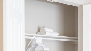 Une buanderie avec un mur blanc, un étendoir et un panier à linge gris.