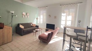 A living room with a sofa, a TV, a coffee table, and a dining table with chairs.