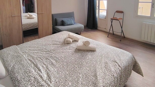 A bedroom with a bed, a wardrobe, a chair, and a radiator.