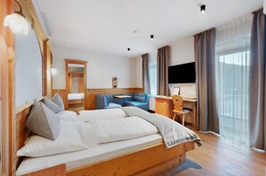 Una habitación de hotel con cama, escritorio, silla, televisor y ventana con cortinas.