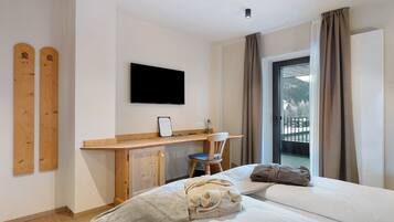 Une chambre d’hôtel équipée d’un lit, d’un bureau, d’une chaise, d’une télévision et offrant une vue sur les montagnes par la fenêtre.