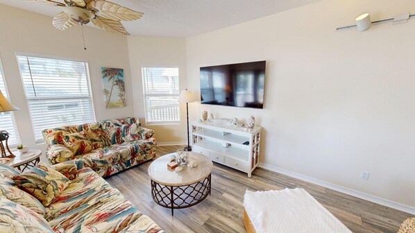 A living room with a sofa, a coffee table, a TV, and a ceiling fan. - Pet Friendly, Remodeled Sandpiper Cove 9222 (Destin)