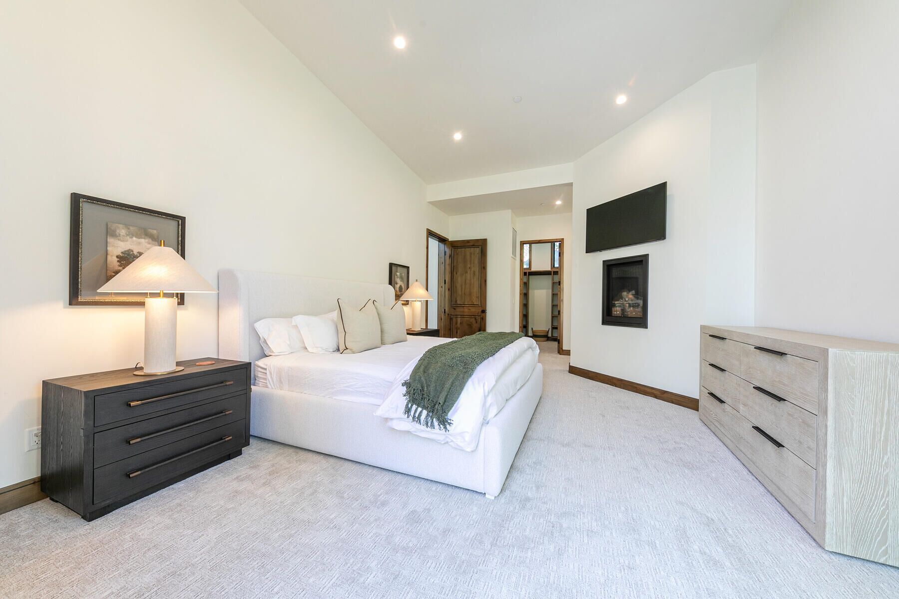 A bedroom with a bed, bedside tables, a dresser, a TV, and a closet.