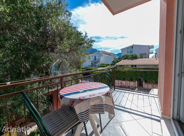 Un balcón con mesa y sillas, con vistas a una zona residencial con casas y árboles.