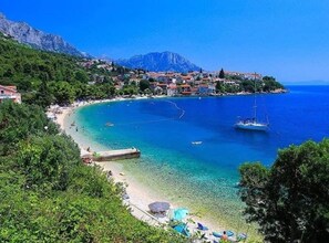 Une ville côtière avec une plage, des bateaux et une montagne en arrière-plan.