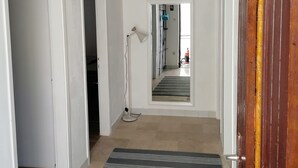 A hallway with a striped rug, a standing lamp, and a door leading to another room. - Apartments Filip & Miroslav (Gradac)
