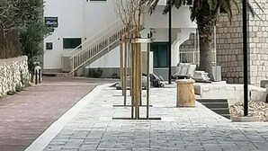 A paved walkway with a stone wall on one side and a building entrance with a staircase. - Apartments Filip & Miroslav (Gradac)