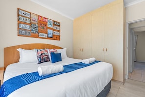 Habitación de hotel con una cama grande, cabecera de madera, pared decorada con placas de matrícula antiguas y un armario amplio.