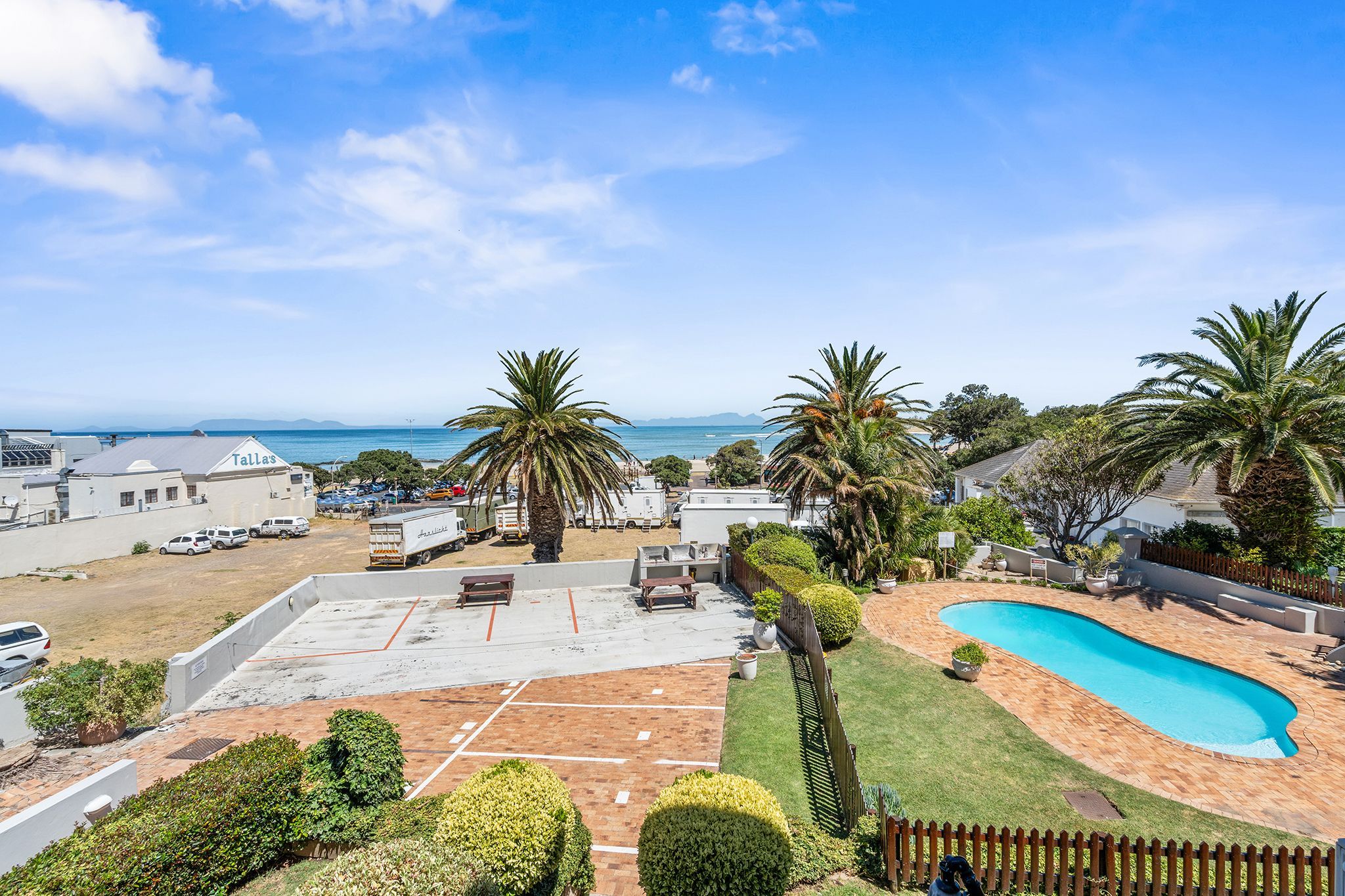 A residential property with a swimming pool, a tennis court, and a view of the ocean.