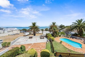 A residential property with a swimming pool, a tennis court, and a view of the ocean. - Gordon's Village View (Cape Town)