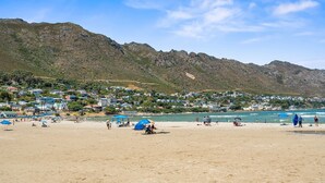Une plage avec des maisons en arrière-plan et une chaîne de montagnes.